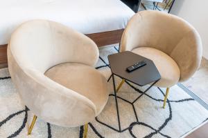 2 chaises et une télécommande sur une table dans l'établissement L'avant-gardiste - Appart'Hotel Le Gatsby, à Saint-Quentin