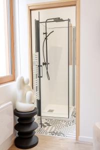 a bathroom with a shower with a white statue on a pole at L'avant-gardiste - Appart'Hotel Le Gatsby in Saint-Quentin