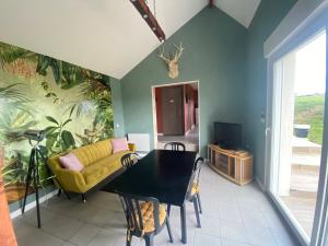 een woonkamer met een tafel en een gele bank bij Gîte de la Prévosserie in Rinxent