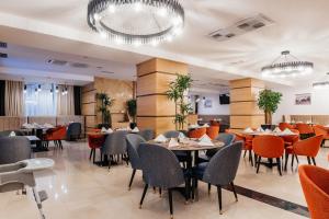 a restaurant with tables and chairs and chandeliers at Ramada by Wyndham Astana in Astana
