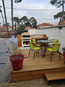 une terrasse en bois avec des chaises, une table et un grill dans l'établissement chez fifi, à Saint-Brévin-les-Pins