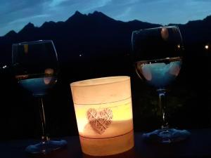 three wine glasses and a candle on a table at FeEl Tatras Direct View apartment in Veľká Lomnica