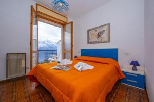 a bedroom with a bed with orange sheets and a window at Appartamenti Secrel in Tremosine Sul Garda