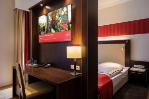 a hotel room with a bed and a desk and a tv at ACHAT Sternhotel Bonn in Bonn