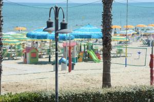 a beach with a playground with umbrellas and the ocean at Camping Village Adriatico Giulianova in Giulianova