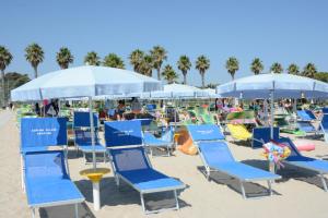 a group of blue chairs and umbrellas on a beach at Camping Village Adriatico Giulianova in Giulianova