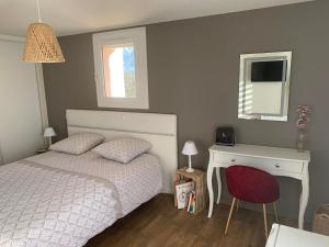1 dormitorio con cama, escritorio y ventana en Domaine de Jarentin - Chambres d'hôtes en Saint-Marcel-de-Félines