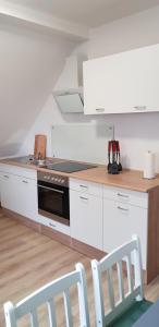 a kitchen with white cabinets and a stove top oven at Ferienwohnung klein Treben 2.0 in Fockendorf
