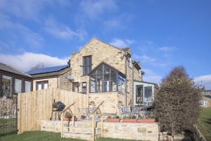 a large stone house with a wooden fence at Oak Lodge House in Leyburn