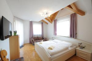 ein Schlafzimmer mit einem weißen Bett in einem Zimmer mit Fenstern in der Unterkunft Appartments Marlena in Niederdorf