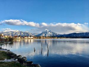 uma grande massa de água com montanhas ao fundo em Hotel Fischer am See em Füssen