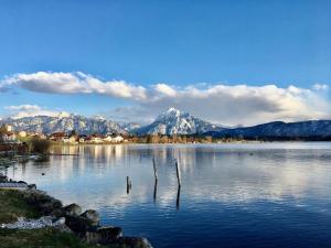 ein großer Wasserkörper mit Bergen im Hintergrund in der Unterkunft Hotel Fischer am See in Füssen
