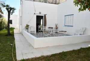 a white building with a patio with a table and chairs at BUNGALOW El HOUDA in Hammamet