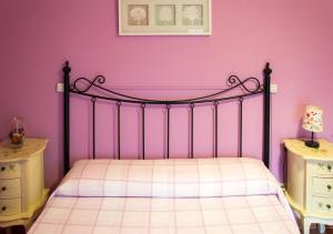 Casa Rural El Fuentarro في Botija: غرفة نوم مع سرير بجدار وردي