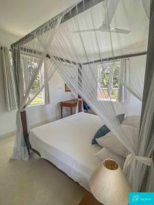 - une chambre avec un lit blanc à baldaquin dans l'établissement Palm Grey Villa By YourHost Vipingo Beach Kilifi, à Kijipwa