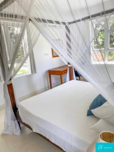 - une chambre avec un lit blanc à baldaquin dans l'établissement Palm Grey Villa By YourHost Vipingo Beach Kilifi, à Kijipwa