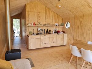 una cocina con armarios de madera y una mesa en una habitación en Refugio Valle Leones, en Puerto Tranquilo