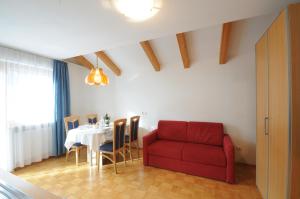 ein Wohnzimmer mit einem Tisch und einem roten Sofa in der Unterkunft Appartments Marlena in Niederdorf
