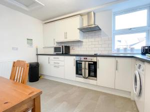 a kitchen with white cabinets and a stove top oven at Spacious 2-bed Apartment in Crewe by 53 Degrees Property, ideal for Business & Professionals, FREE Parking - Sleeps 3 in Crewe