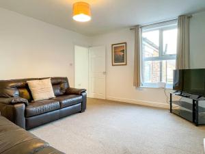 a living room with a leather couch and a television at Spacious 2-bed Apartment in Crewe by 53 Degrees Property, ideal for Business & Professionals, FREE Parking - Sleeps 3 in Crewe