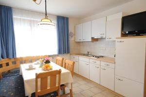 eine Küche und ein Esszimmer mit einem Tisch und einem TV in der Unterkunft Appartments Marlena in Niederdorf