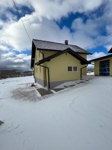 een geel huis met sneeuw op de grond bij Kuća za odmor IVKOVIĆ in Kupres