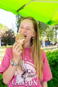 een jong meisje dat een donut eet met een paraplu bij TopParken - Resort Veluwe in Garderen