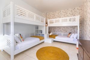 2 białe łóżka piętrowe w pokoju z dywanem w obiekcie Villa Penguina Play Blanca Lanzarote w mieście Playa Blanca