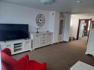 a living room with a tv and a red chair at Hotel Logos in Warsaw