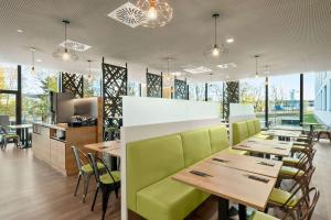 a restaurant with wooden tables and green chairs at Super 8 by Wyndham Munich City North in Munich