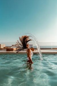 uma mulher está de pé na água numa piscina em Blue Gres Villa Tinos em Tinos