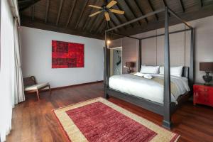 a bedroom with a canopy bed and a red painting at Surin Heights Villa in Surin Beach