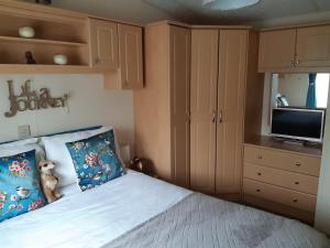 a bedroom with a bed and a flat screen tv at 24 The Beeches Caravan Park in Gilcrux
