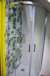 La salle de bains est pourvue d'une douche avec rideau de douche. dans l'établissement Pastelowy Domek, à Załakowo
