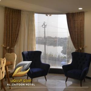 a living room with two chairs and a large window at Al-Zaitoon Hotel and Restaurant فندق ومطعم الزيتون in Ḩujrat Farhūd