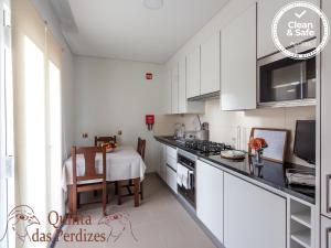 a kitchen with white cabinets and a table and a dining room at Quinta das Perdizes in Ponta Delgada