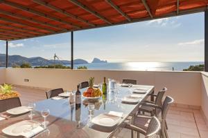 a dining table on a balcony with a view of the ocean at Villa Nubita in Sant Josep de sa Talaia