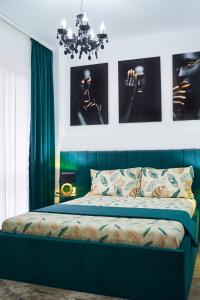 a bedroom with a bed with green curtains and a chandelier at New Apartments IuliusMall-Apartamente cu 2 camere in Iaşi