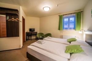 a bedroom with two beds and a desk and a window at Hotel Koruna Prachatice in Prachatice
