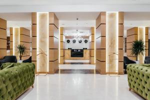 a lobby of a hotel with green couches at Ramada by Wyndham Astana in Astana