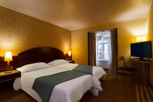 a bedroom with a large bed and a television at Hotel Internacional Porto in Porto