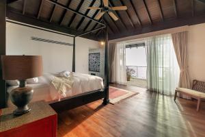 een slaapkamer met een bed en een groot raam bij Surin Heights Villa in Surin Beach