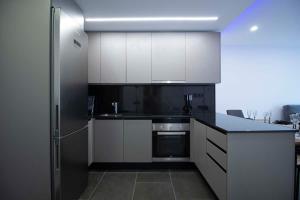 a kitchen with white cabinets and a stainless steel refrigerator at Apartamento Moderno a 5 min. Funicamp in Encamp