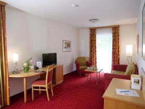 Habitación de hotel con escritorio, sillas y TV. en Hotel Garni Christl, en Bad Griesbach