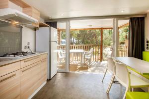 a kitchen with wooden cabinets and a balcony with a table at Camping la Croix du Sud in Saint-Tropez