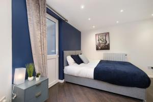 een slaapkamer met een bed en een blauwe muur bij Kings House Apartment Hayes, West London Apt A in Northolt