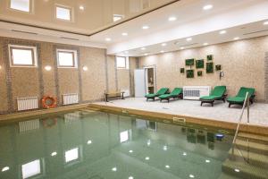 a swimming pool with green chairs and a table at Ramada by Wyndham Astana in Astana