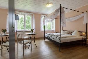 SaupsdorfにあるKräuterbaudeのベッドルーム(天蓋付きベッド1台、テーブル、椅子付)