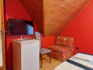 a room with a red wall with a tv and a chair at Napfény villa in Balatonfüred