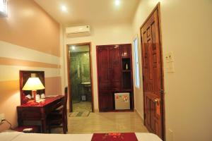 a bedroom with a bed and a desk and a door at Hong Thien Ruby Hotel in Hue